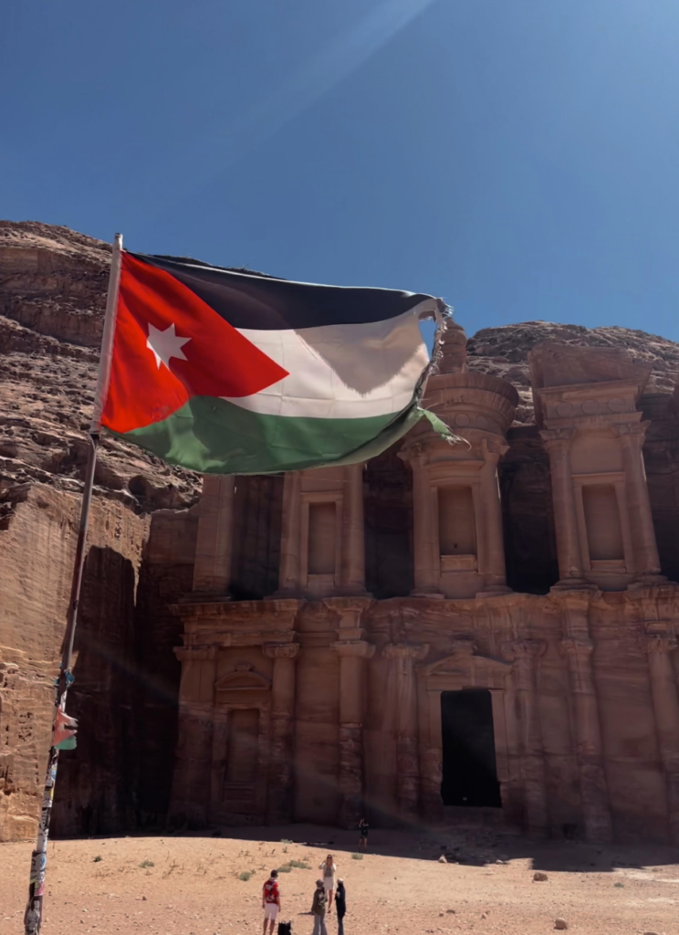 A Jordanian flag waves in front of the Monastery's facade.